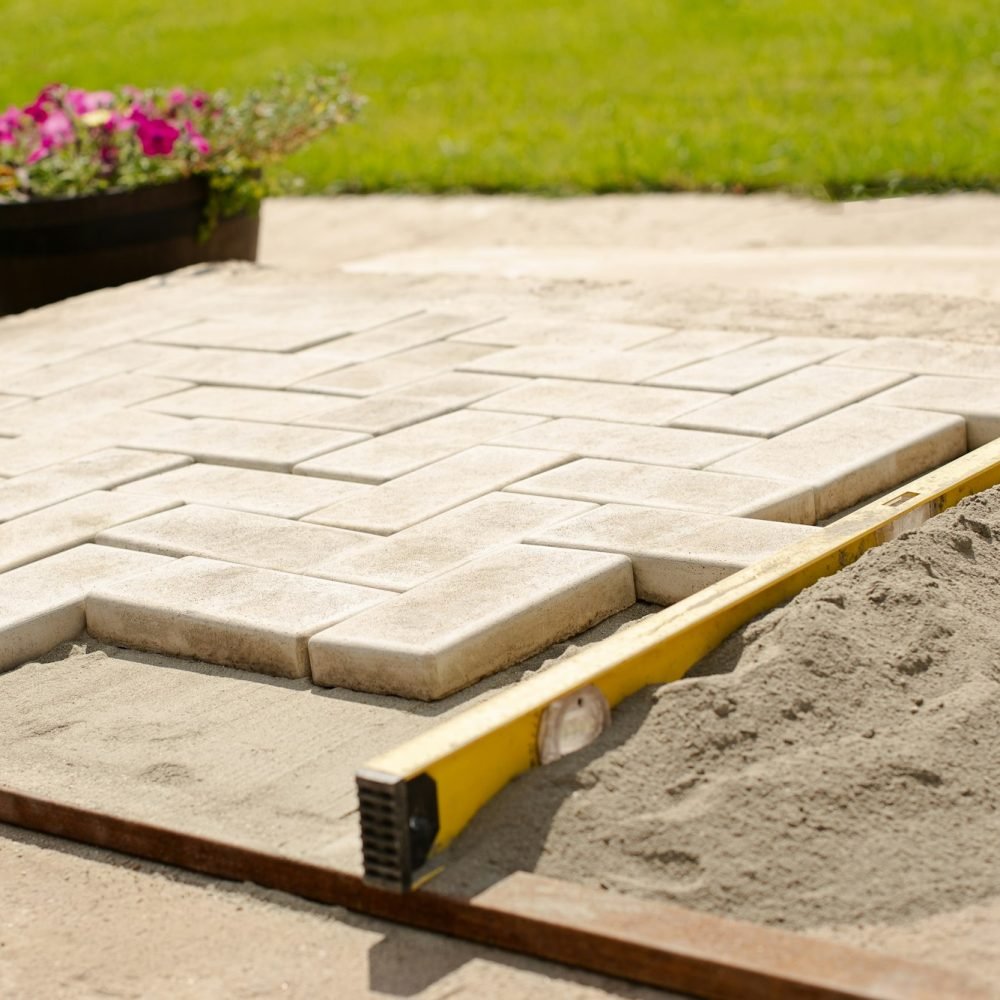 The master lays paving stones in layers. Garden brick pathway paving by professional paver worker.